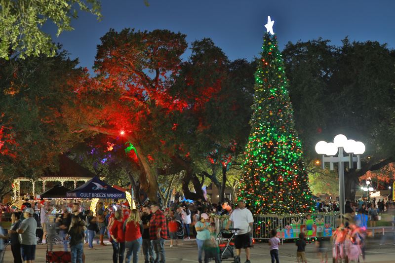 A 30-foot lit Christmas tree at a crowded DeLeon Plaza at night