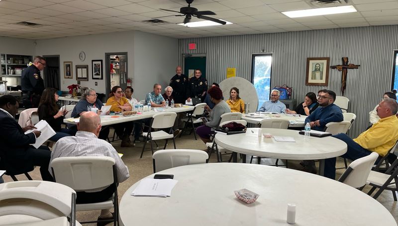 A large group of people sitting at folding chairs and tables at Christ's Kitchen