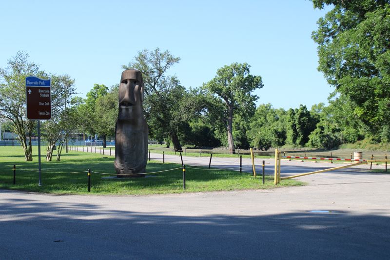 Riverside Park Easter Island head next to a road with a closed gate