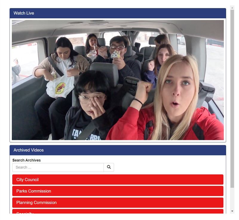 Eight teenagers sit in the back of a van. Some of them make fist pump motions.