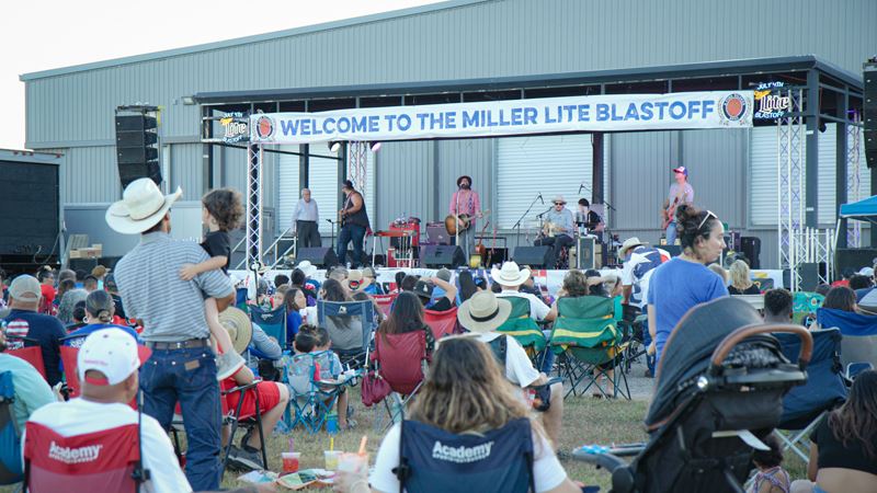 A crowd at the community center ground watches a band with 4 guitarists and a drummer