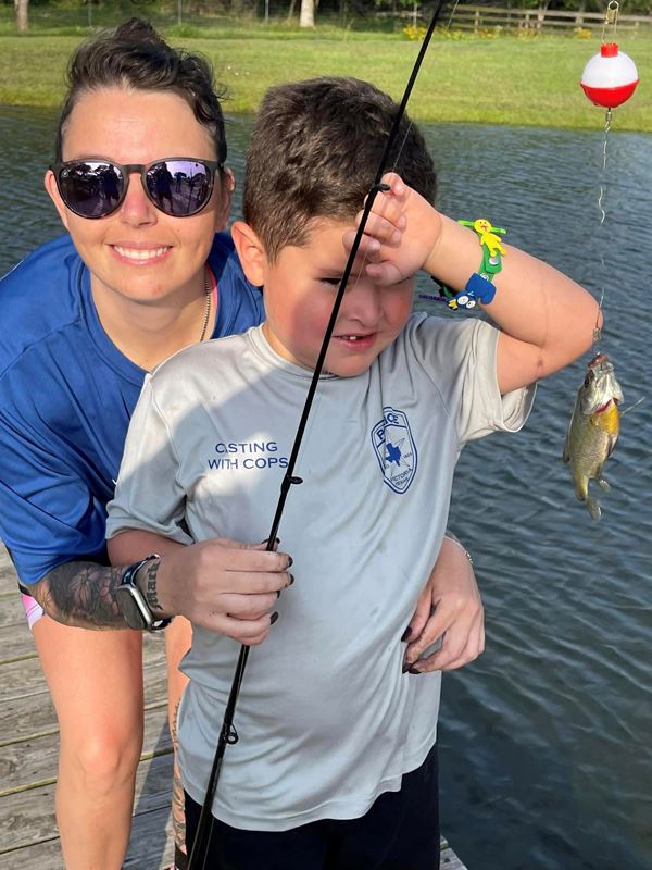A woman and a boy holding a fishing rod with a fish