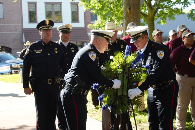 Police officers place a memorial wreath while Police Chief Chuck Young looks on