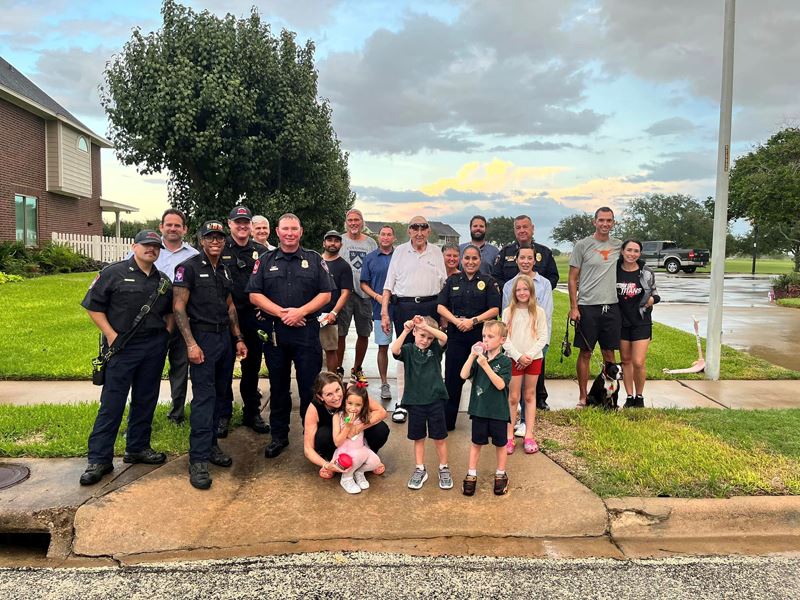 Group photo on a sidewalk. Some people in the photo wear police uniforms.