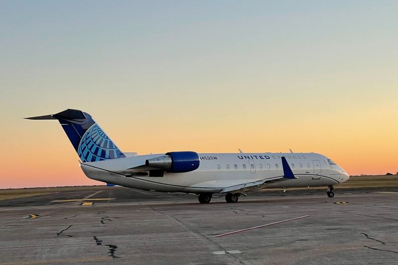 A United Express 50 passenger jet on the runway at sunrise