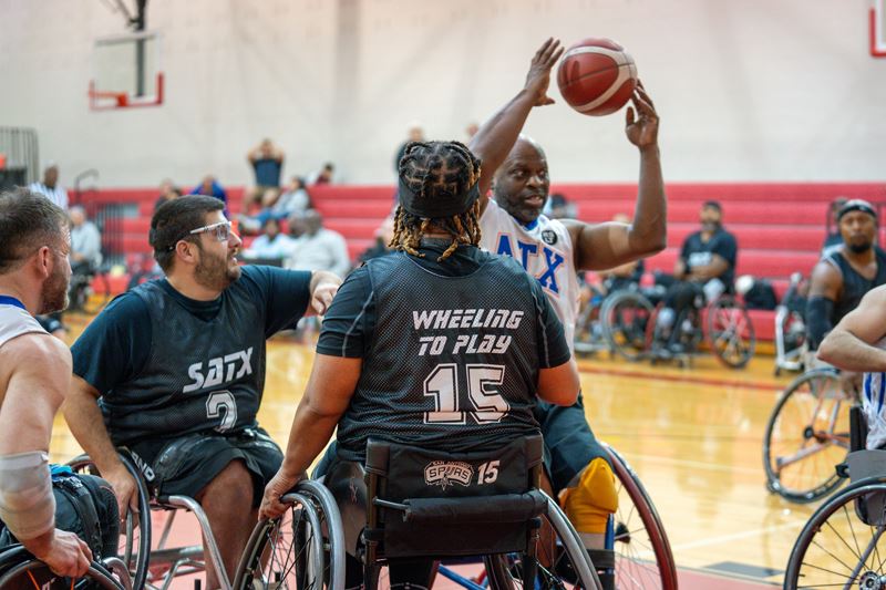 Wheelchair basketball players attempt to take the ball from another player