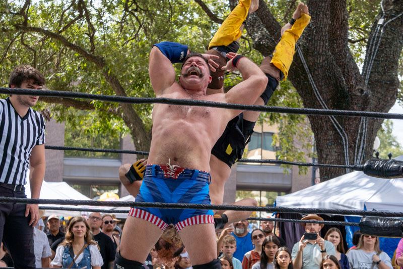 A wrestler flips another wrestler while a crowd watches