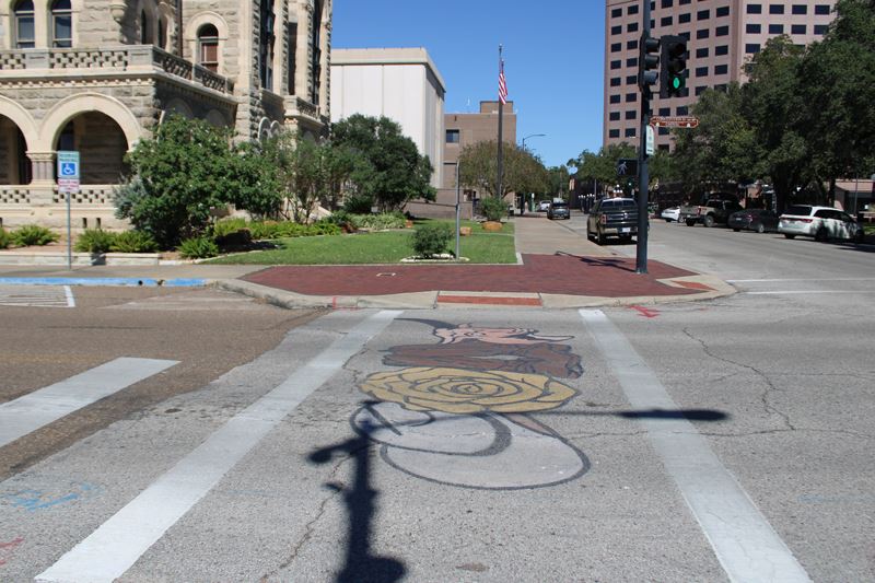 Crosswalk artwork near the Victoria County courthouse with a cowboy hat, boots, yellow rose, & steer