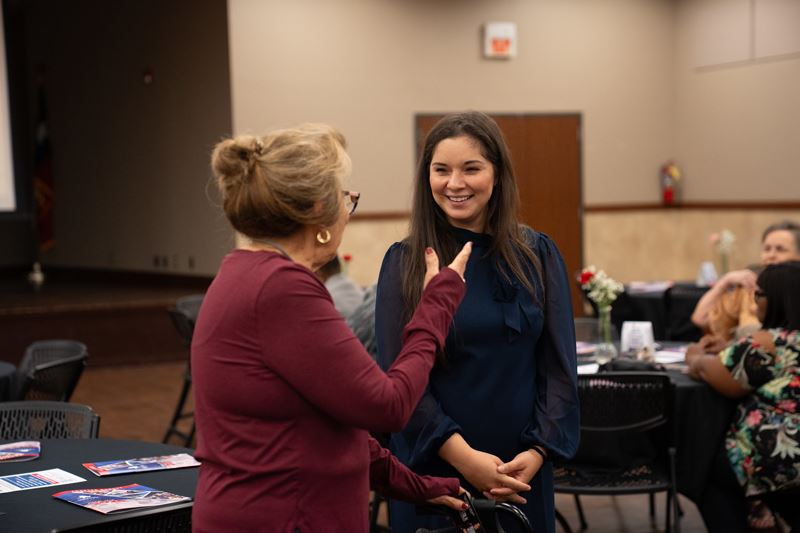 A smiling woman talking with another woman who is gesturing