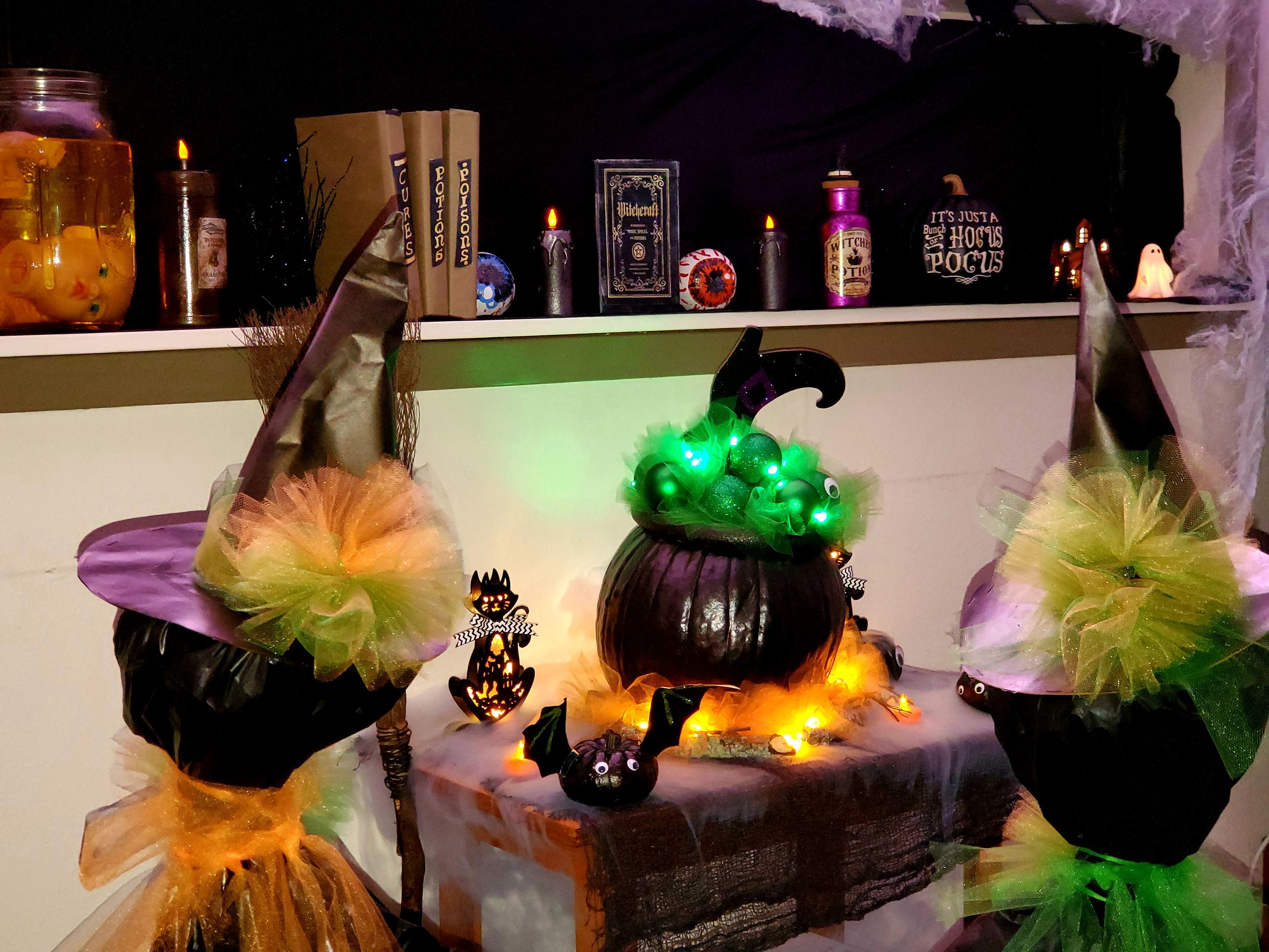 Pumpkin painted as cauldron with green lights and Christmas ornaments for bubbles. Witch memorabilia