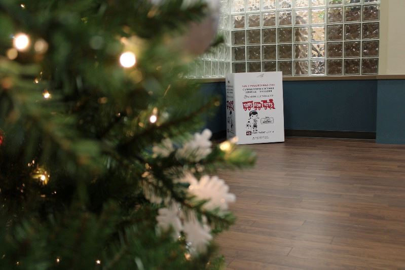 A Toys for Tots donation box sits in the hallway with a Christmas tree in the left foreground.