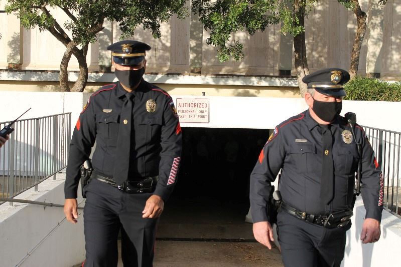 Two uniformed police officers walk out of basement-level entrance to Victoria Police Department.