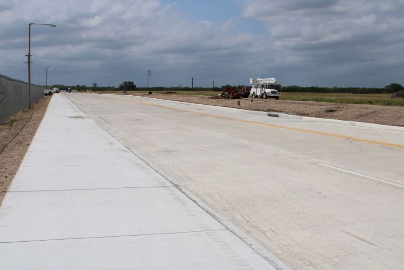 Placido Benavides Drive, with freshly paved sidewalk, construction truck in background