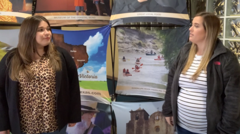 Two women stand in front of an Explore Victoria backdrop.