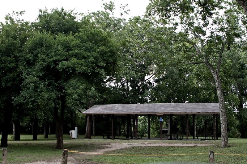 A wide roofed concrete pavilion in a grassy area