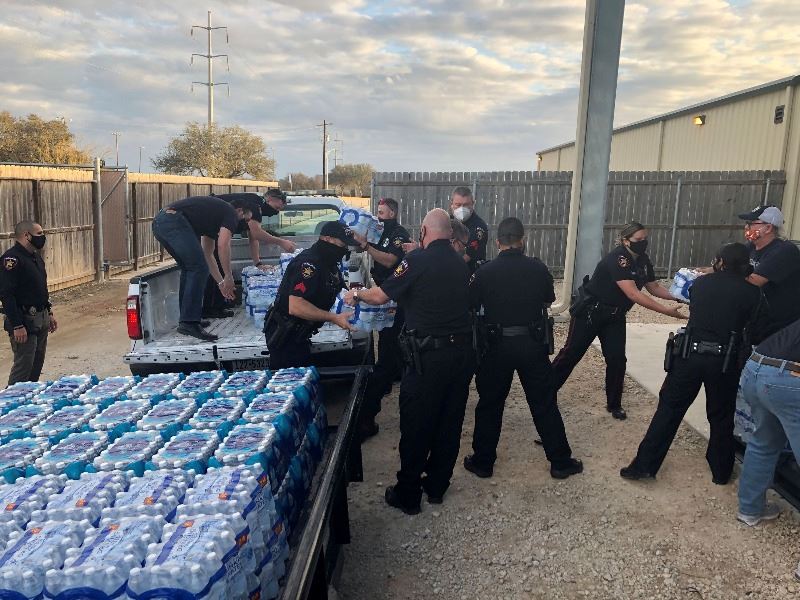Workers load cases of bottled water onto a flatbed trailer