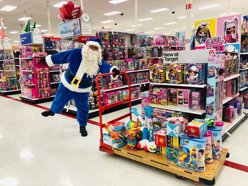 Blue Santa pushes a shopping cart full of toys at Target.