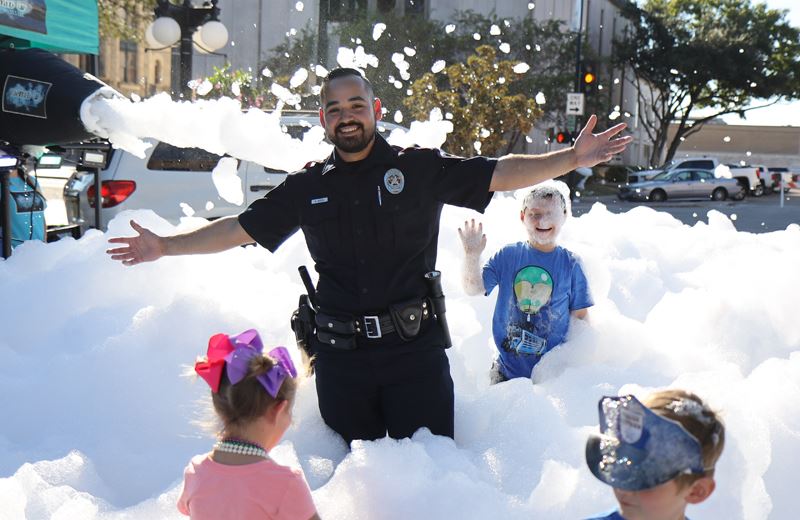 Police officer running through foam pit with kids