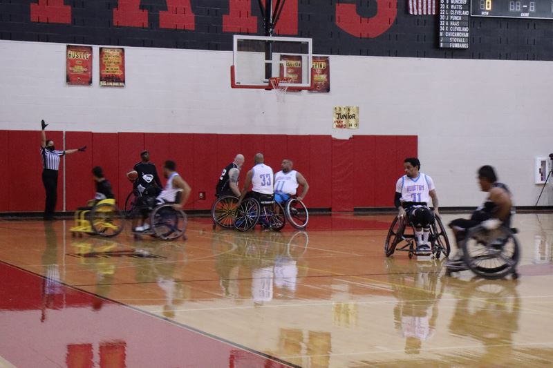 Wheelchair basketball players play on an indoor basketball court.
