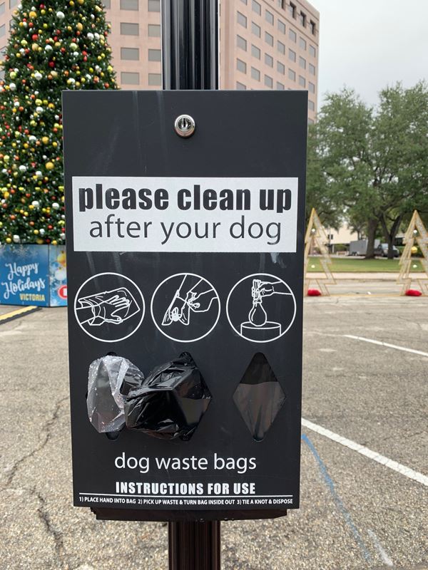 A plastic bag dispenser labeled Please clean up after your dog