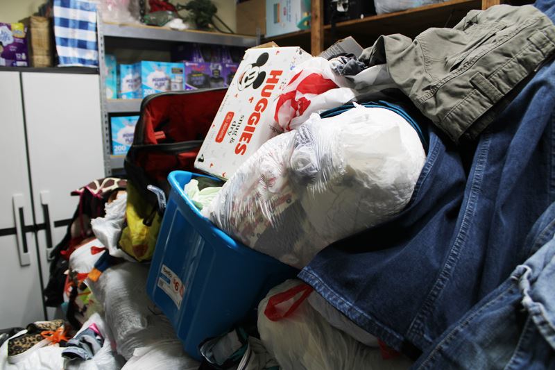 A pile of donated goods, including clothes, a stuffed trash bag and a diaper box