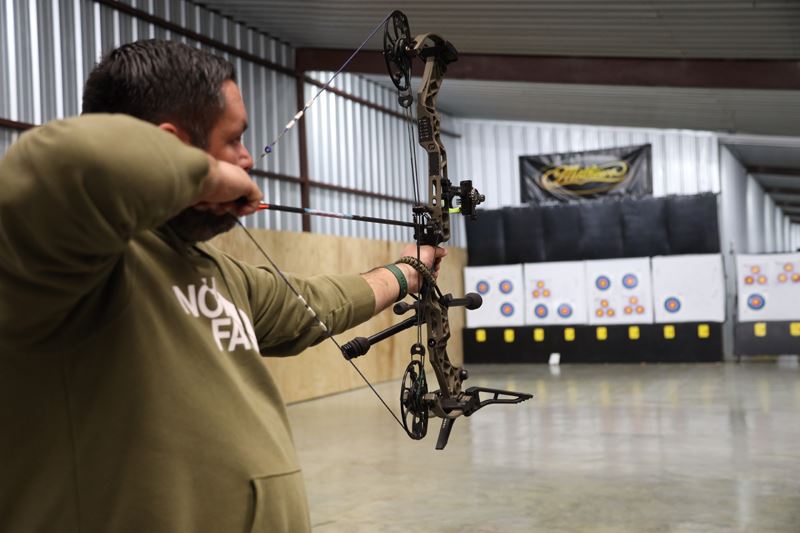 An archer aims at a target in an indoor archery range