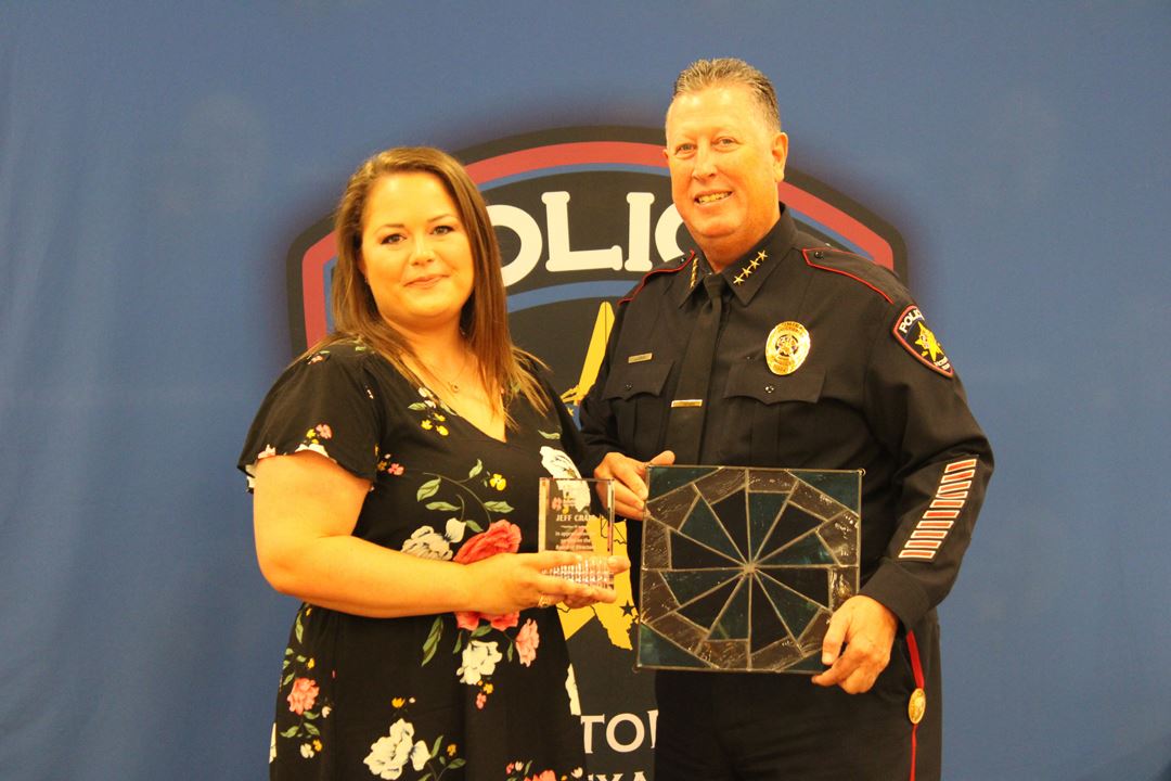 Meagan Burrow presents J.J. Craig with a plaque and a commemorative stained glass pinwheel