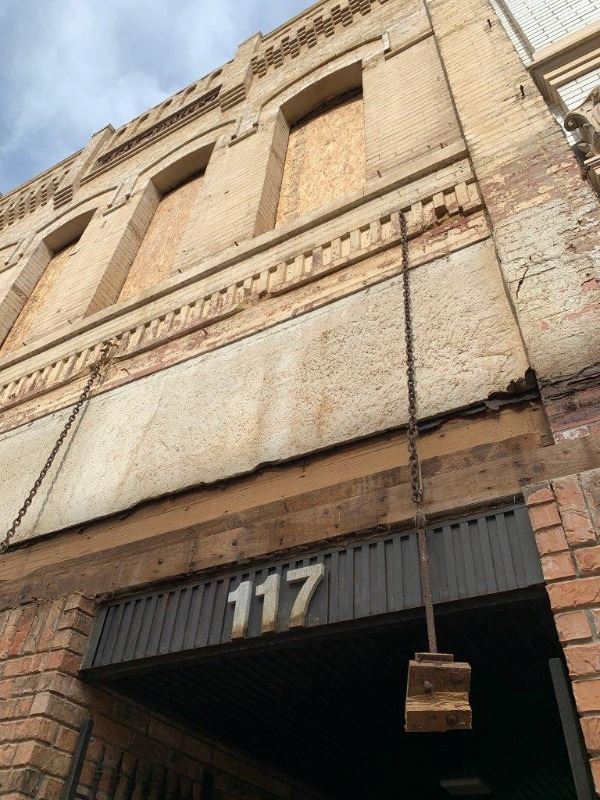 An office building downtown shows a fresh, blank facade after a recent awning demolition