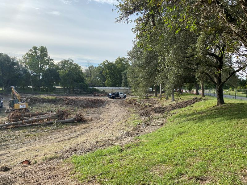 The Riverside Park duck pond is excavated. Heavy machinery sits in the empty pond with felled trees.